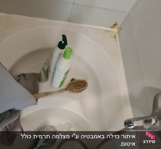 מקלחת עם בקבוקי שמפו, מברשת ונזילת חלודה